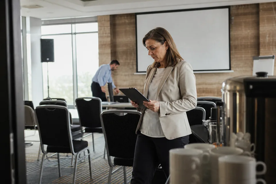 Menedżerka wydarzeń sprawdza przygotowanie sali konferencyjnej w hotelu przed szkoleniem firmowym
